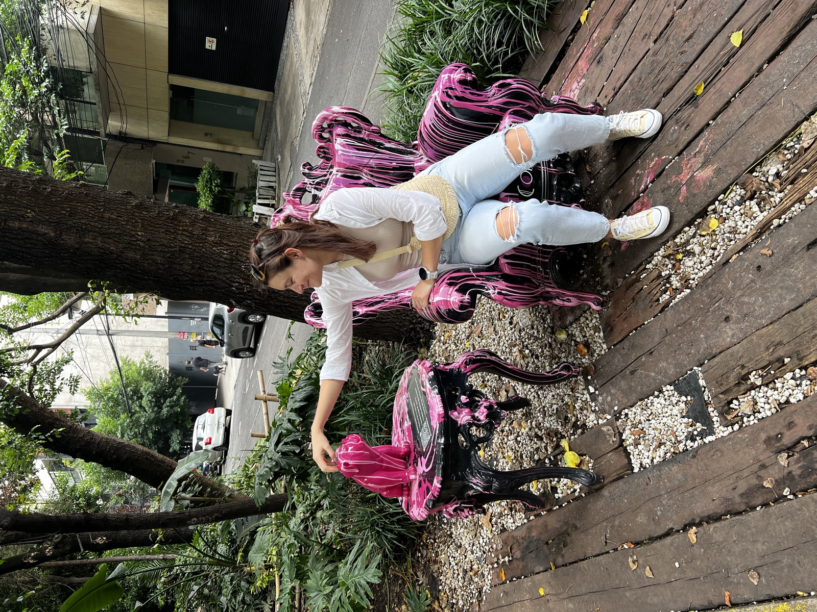 Clara seated on a hand-painted bench in a leafy courtyard